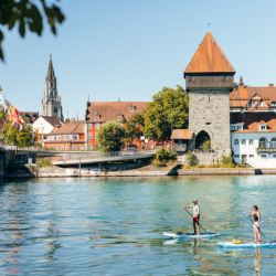 A river side shot of a couple paddleboarding on the River in Konstanz, Germany